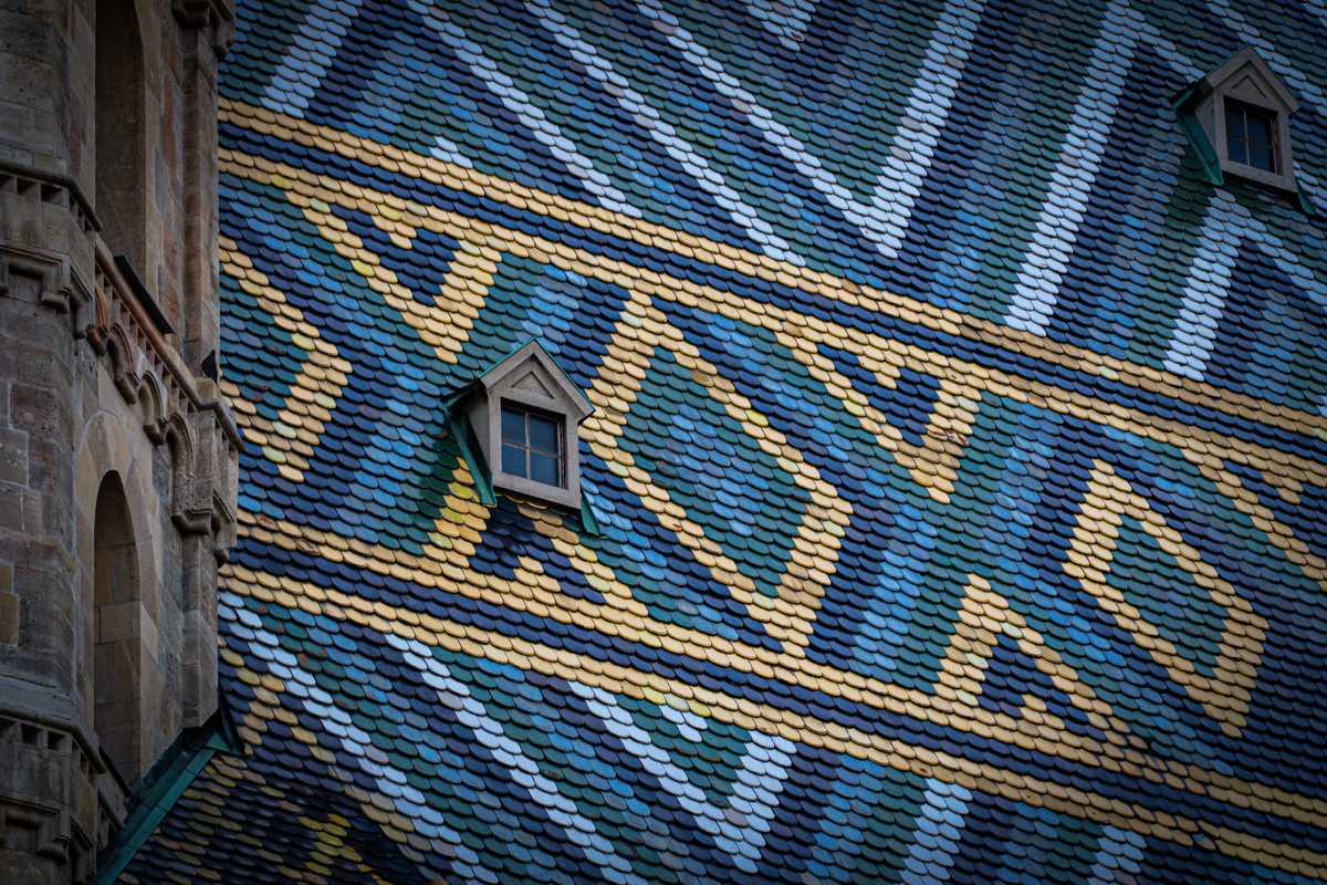 Close-up of the patterned chevron tile roof of a European cathedral with two small dormer windows